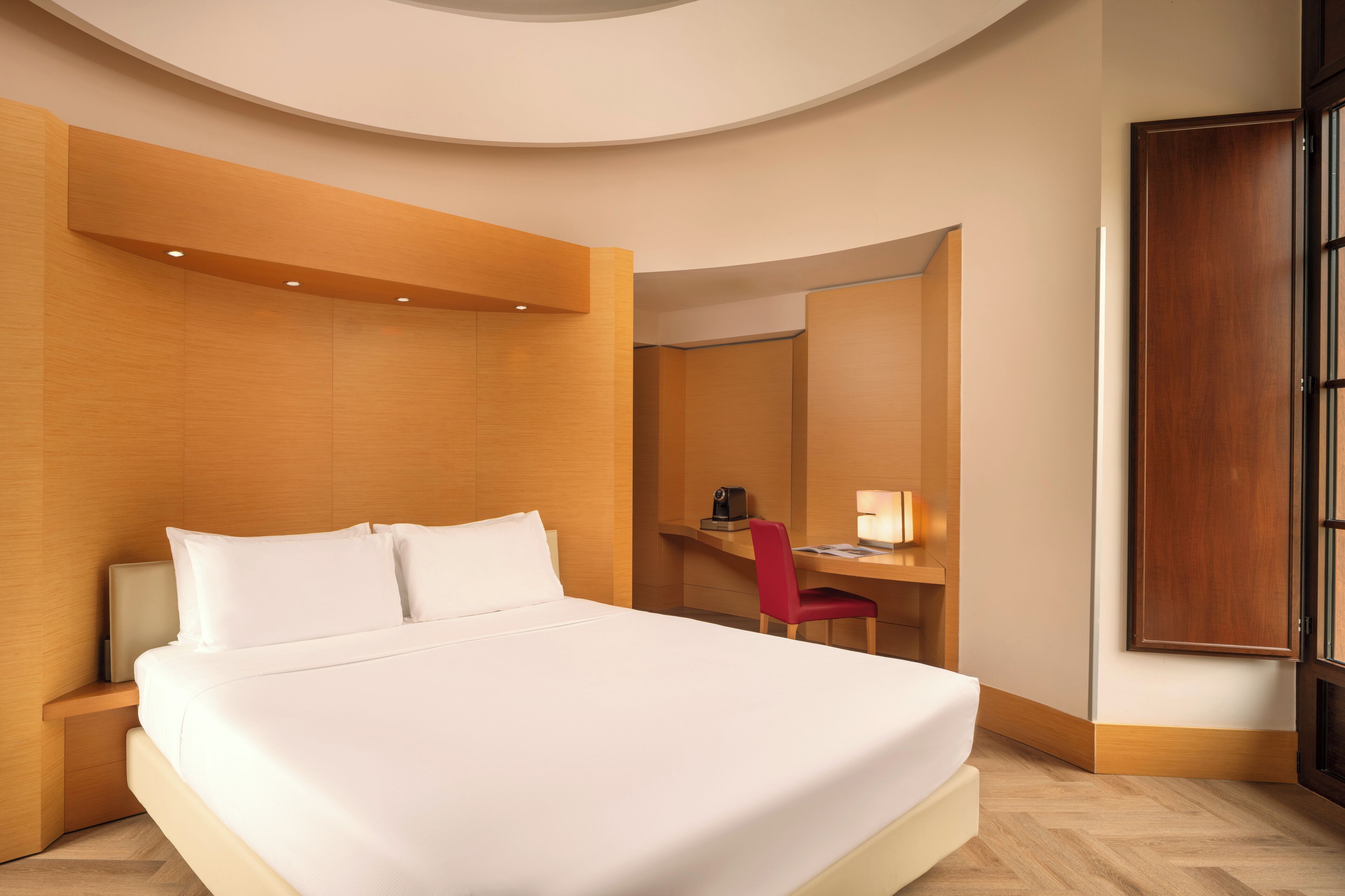 Una habitación de hotel moderna con una cama grande, un escritorio y una silla.
