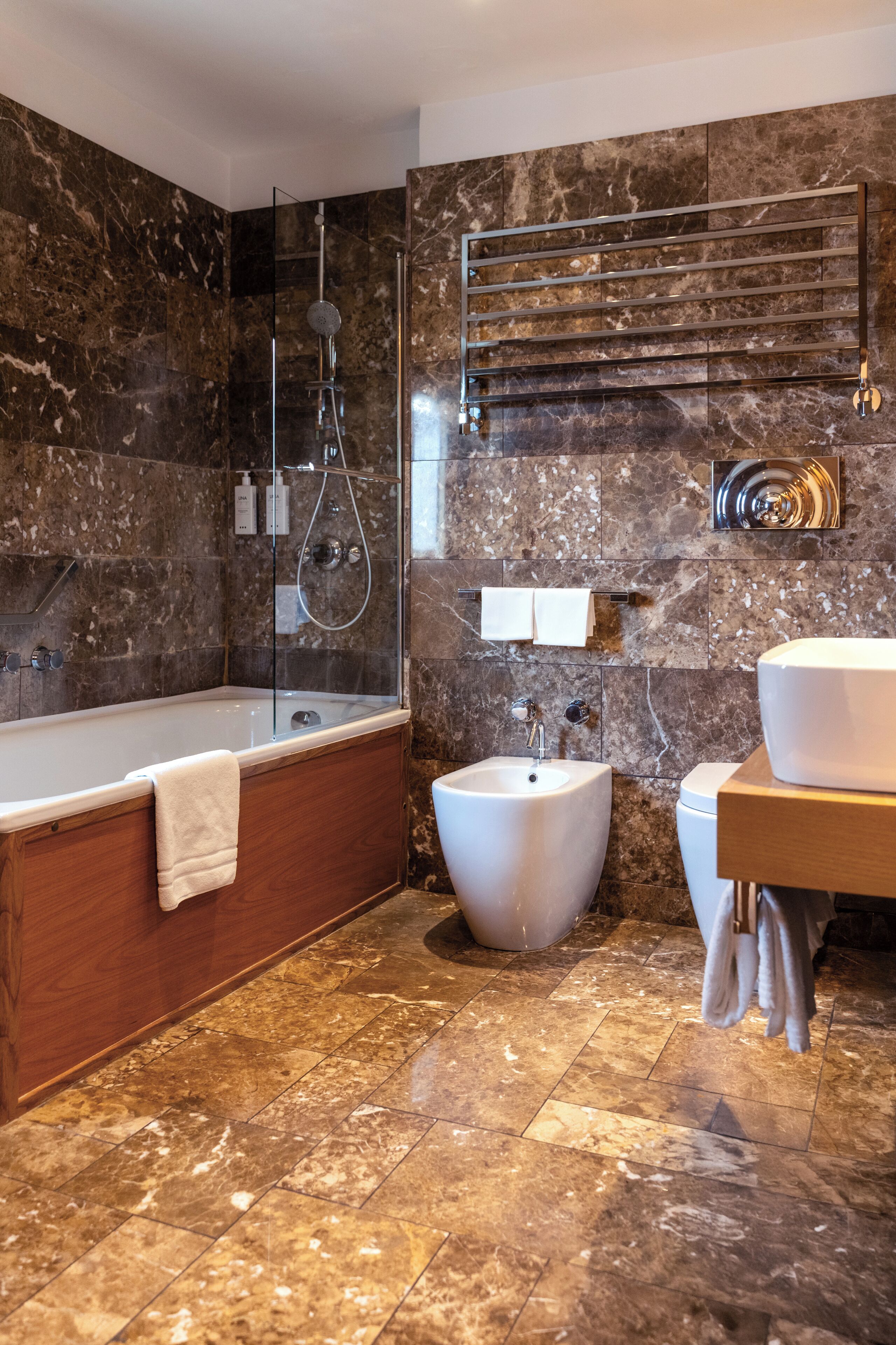 Une salle de bain moderne avec une baignoire sur pieds, un bidet et un meuble-lavabo avec un évier et un miroir.