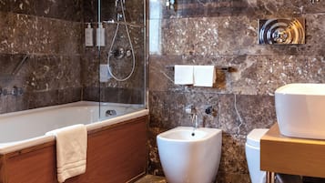 Une salle de bain moderne avec une baignoire sur pieds, un bidet et un meuble-lavabo avec un évier et un miroir.
