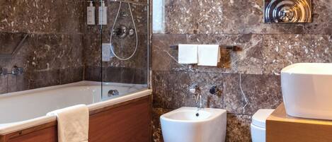 Une salle de bain moderne avec une baignoire sur pieds, un bidet et un meuble-lavabo avec un évier et un miroir.