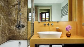 Un baño moderno con bañera, un espejo grande y un mueble de tocador de madera con lavabo.