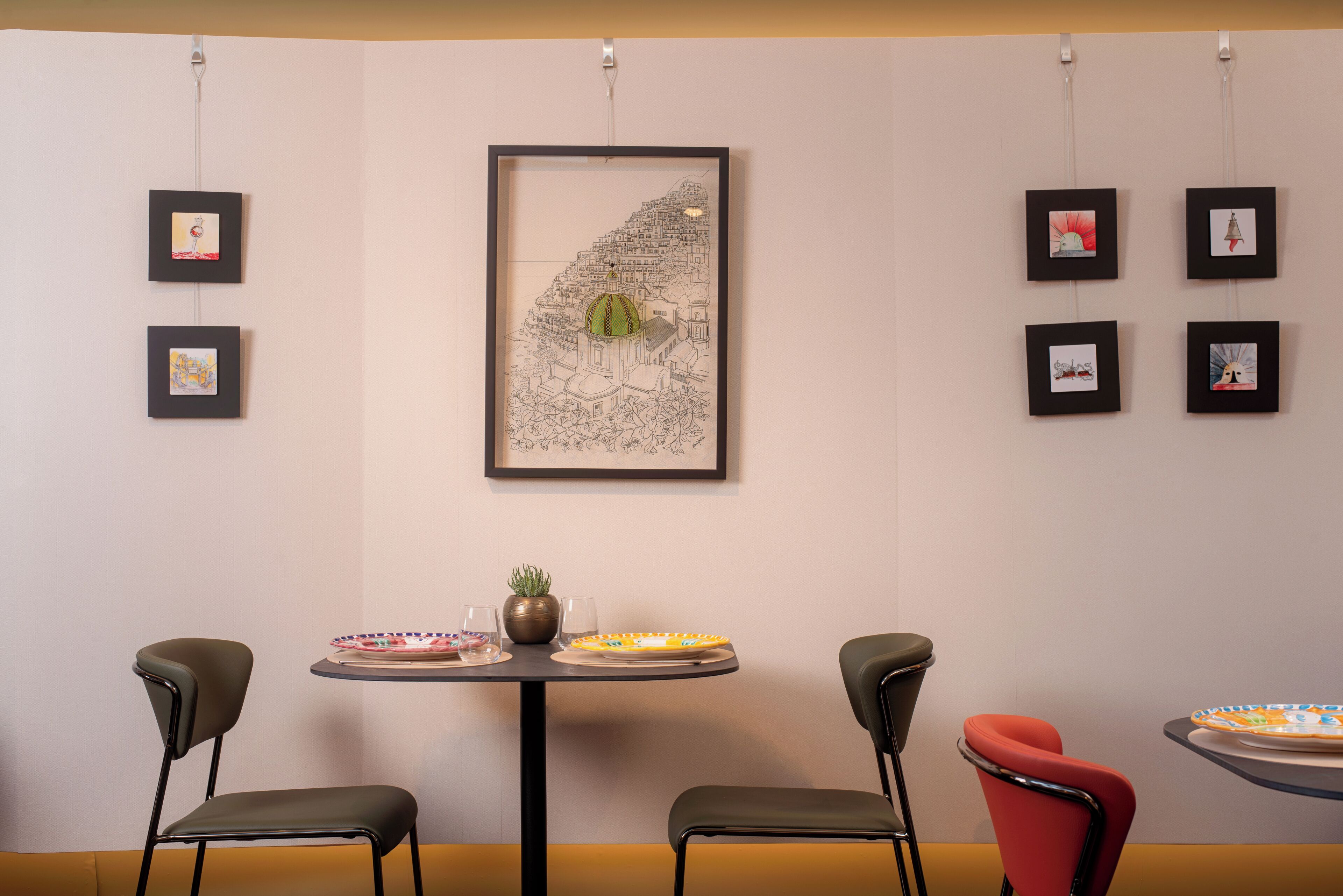 A dining area with a table, chairs, and framed artwork on the wall.