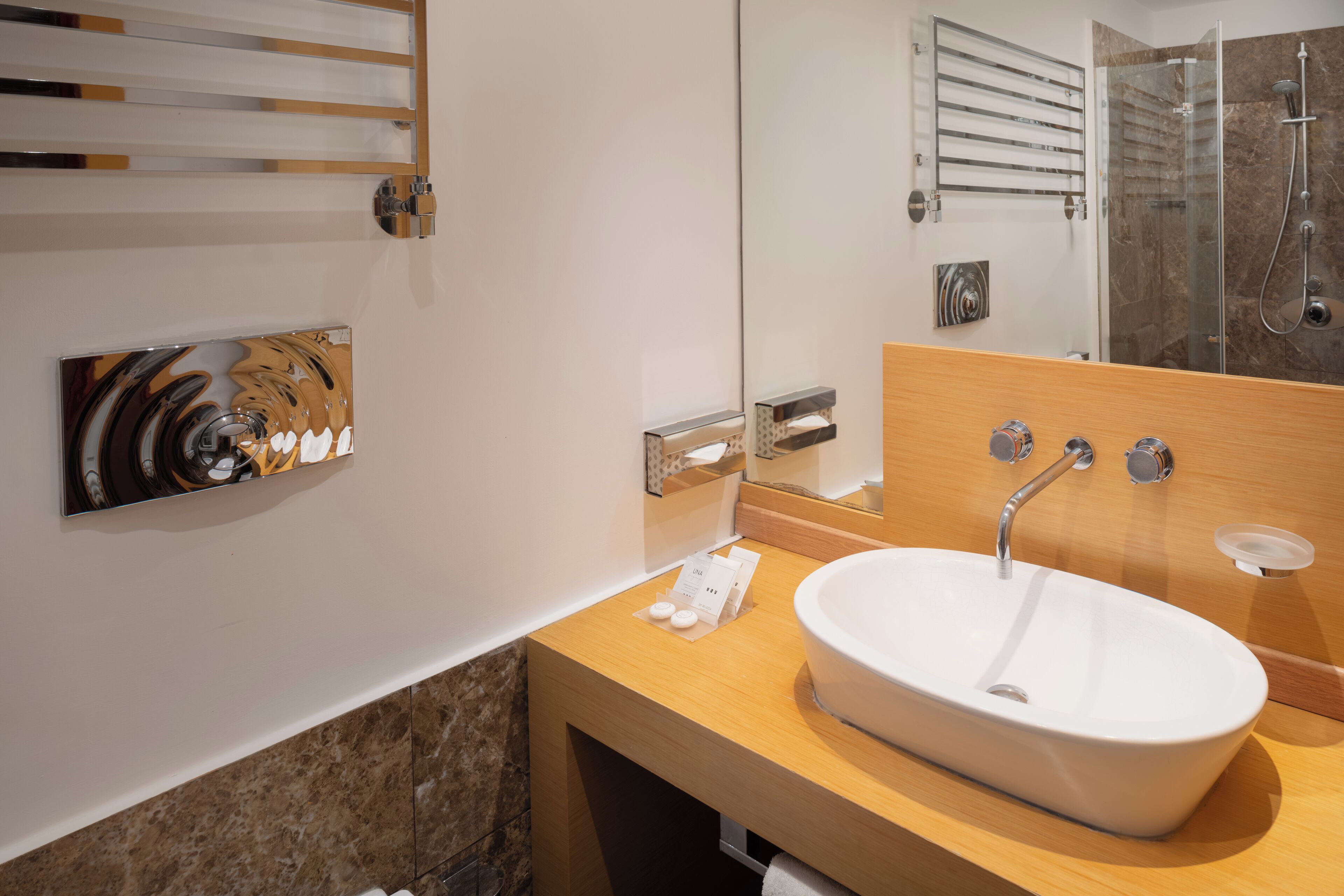 A modern bathroom with a large mirror, a white sink, and a shower area.
