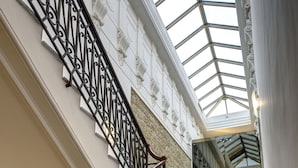 A marble staircase with ornate black iron railings leading to a glass-paneled upper level. - UNA Hotels Napoli (Naples)