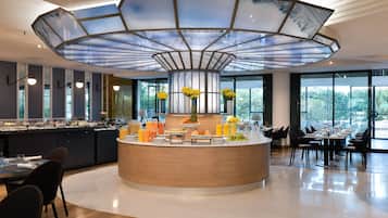 A modern breakfast bar with a central island, surrounded by seating and large windows offering views of the outdoors.