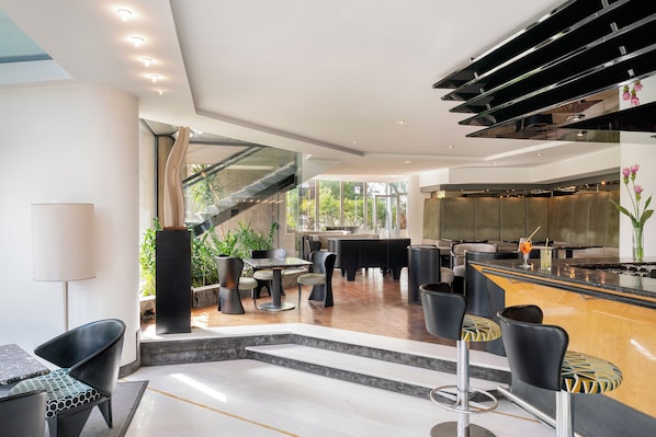 A modern hotel lobby with a bar area, seating, and a staircase leading to upper floors.
