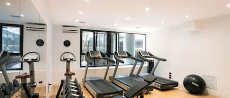 A gym with treadmills, elliptical machines, and free weights.