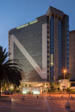 Un hotel moderno con una fachada geométrica llamativa y una entrada grande e iluminada.