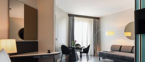 Une chambre d’hôtel équipée d’un lit, d’un bureau, d’une chaise, d’un canapé et d’une télévision.