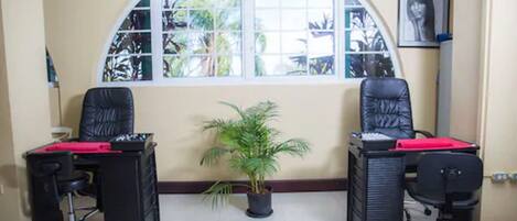 A room with two black office chairs, a desk with a red folder, and a potted plant.