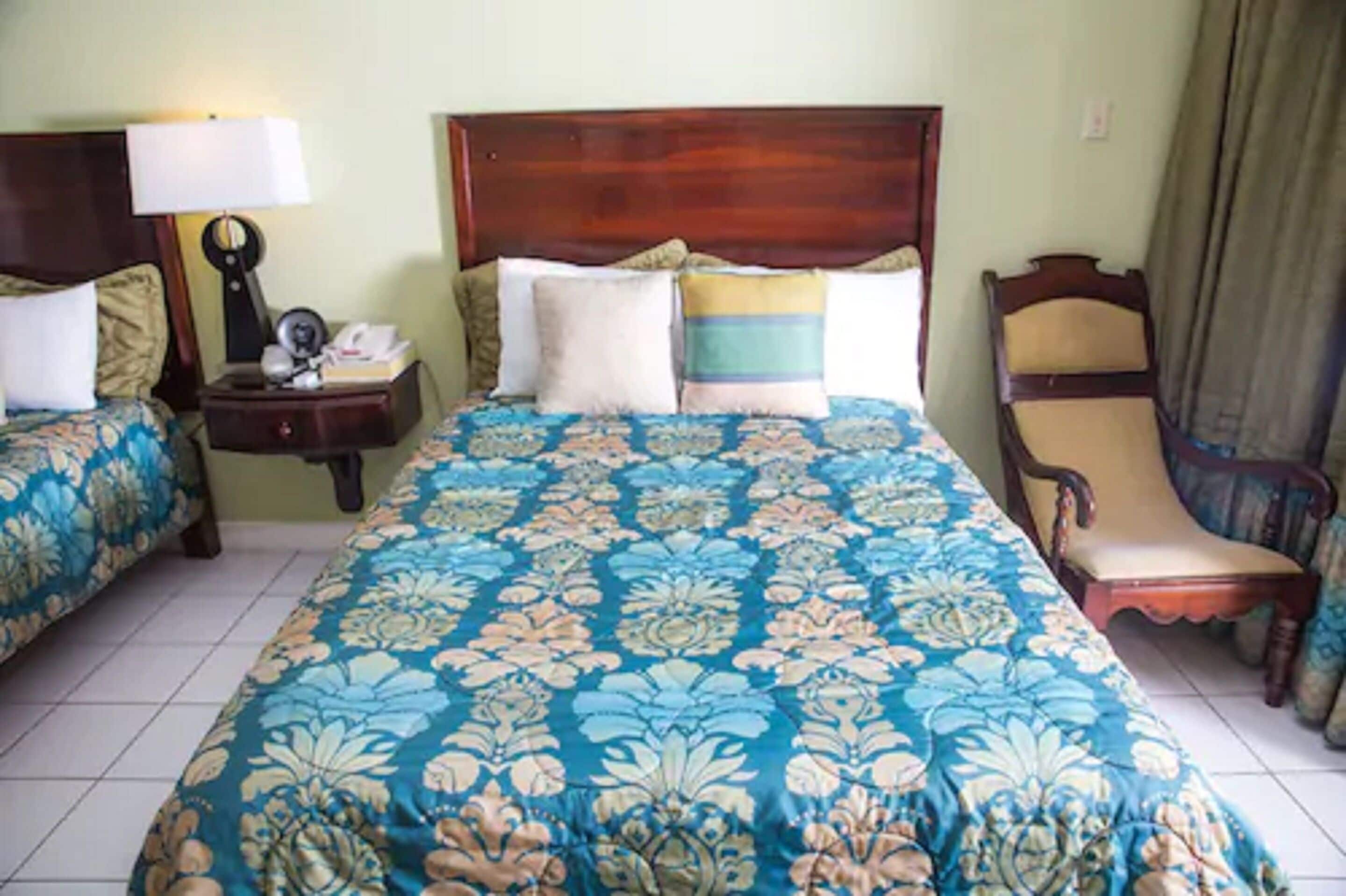 Une chambre d’hôtel avec un grand lit, deux tables de chevet, une chaise et une lampe.