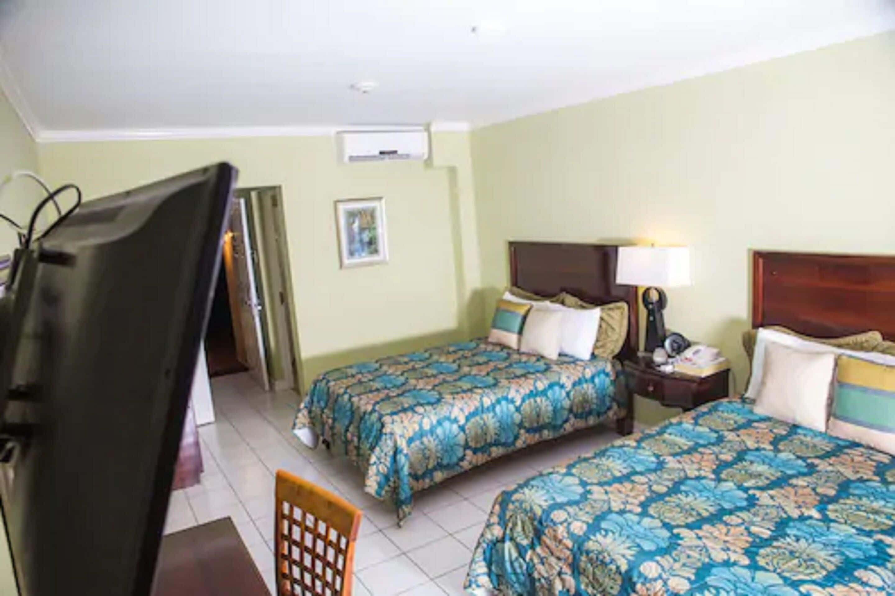 Ein Hotelzimmer mit zwei Betten, einem Fernseher, einem Schreibtisch und einem Stuhl.
