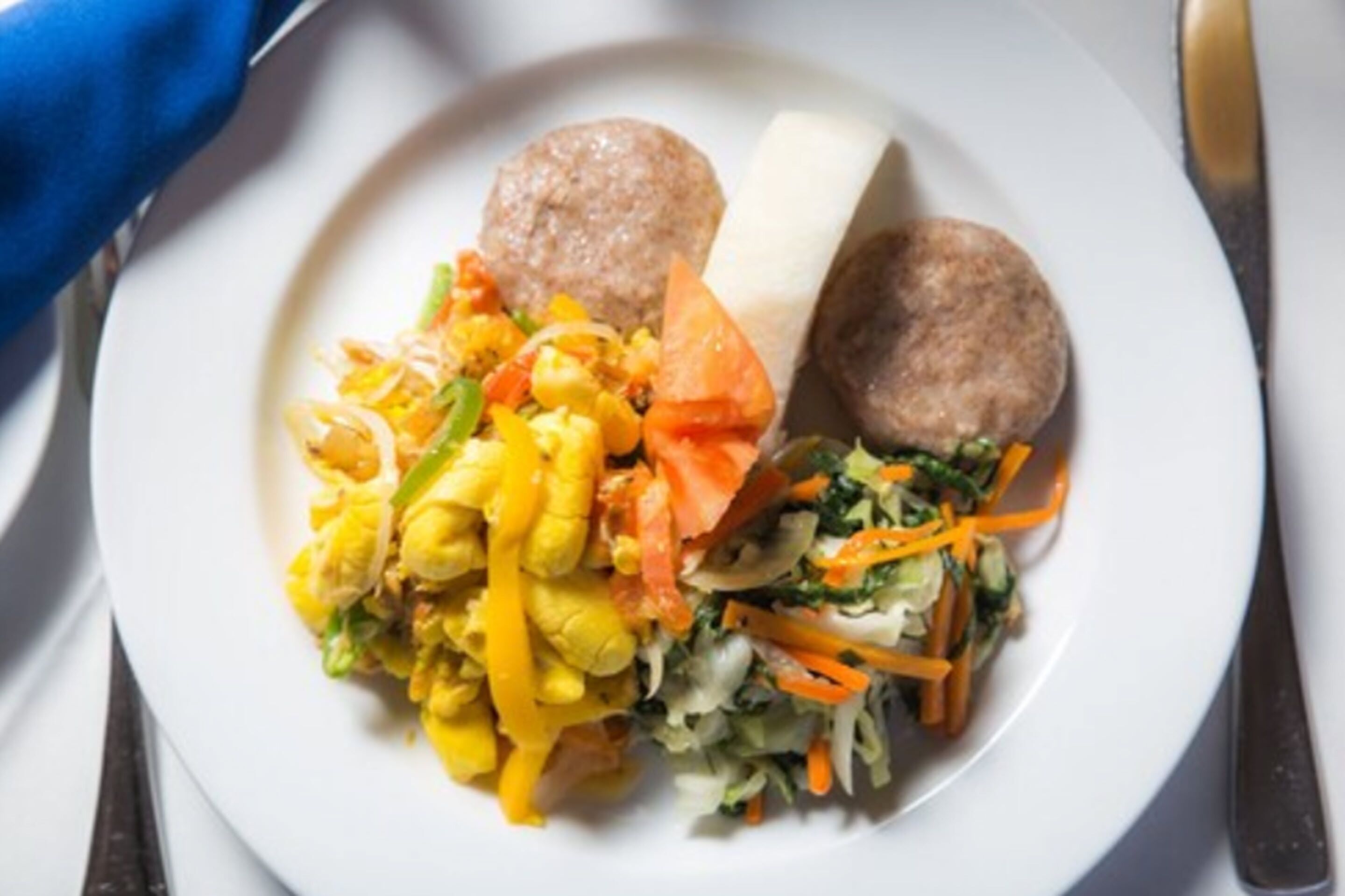 Un plato con huevos revueltos, salchicha, ensalada de col y una rebanada de pan.