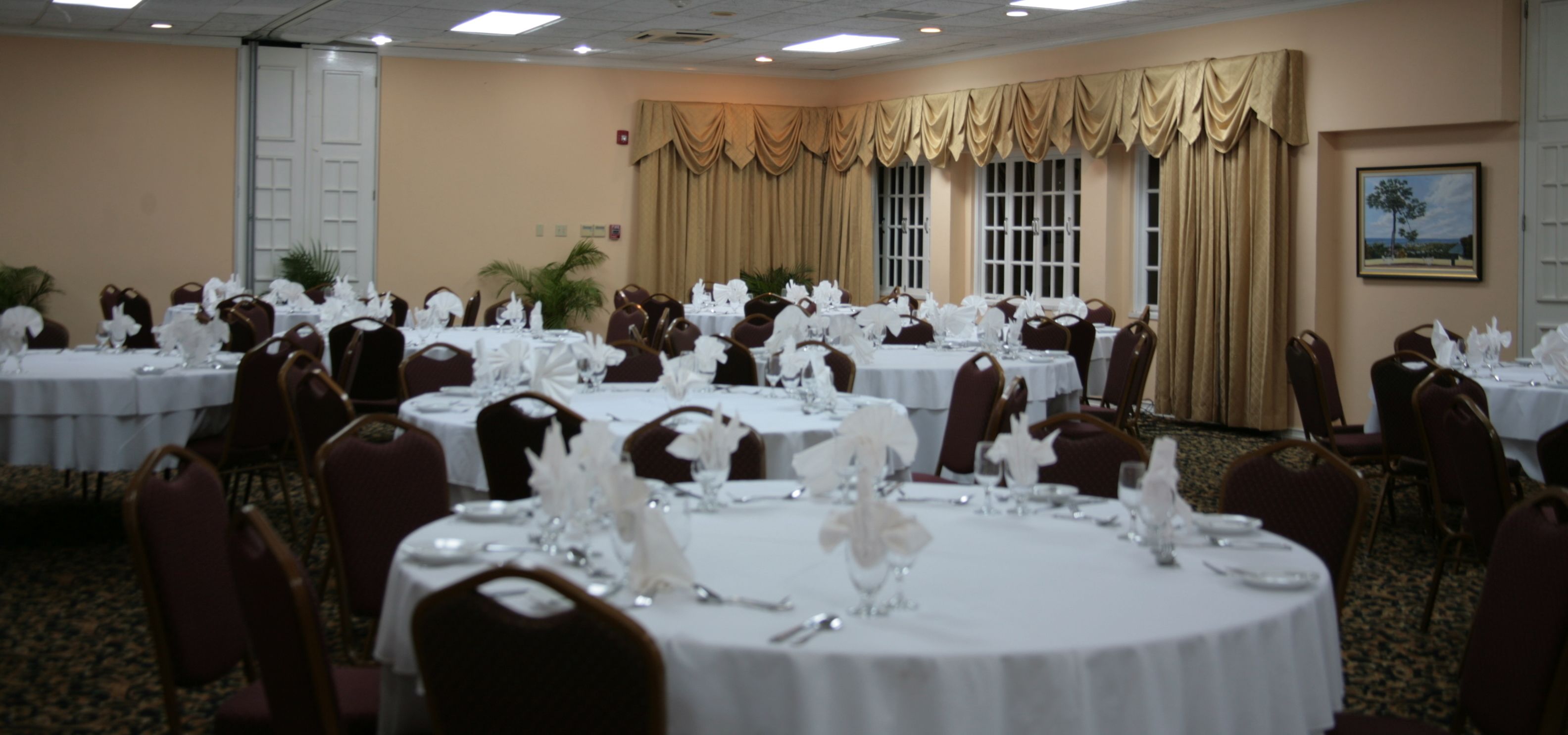 A banquet hall with round tables set for dining, arranged in rows.