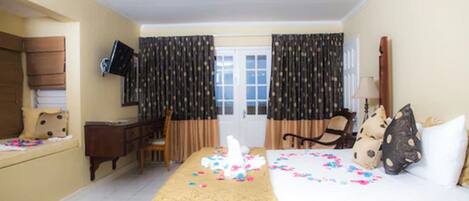 A hotel room with a bed, a desk, a chair, a television, and curtains.