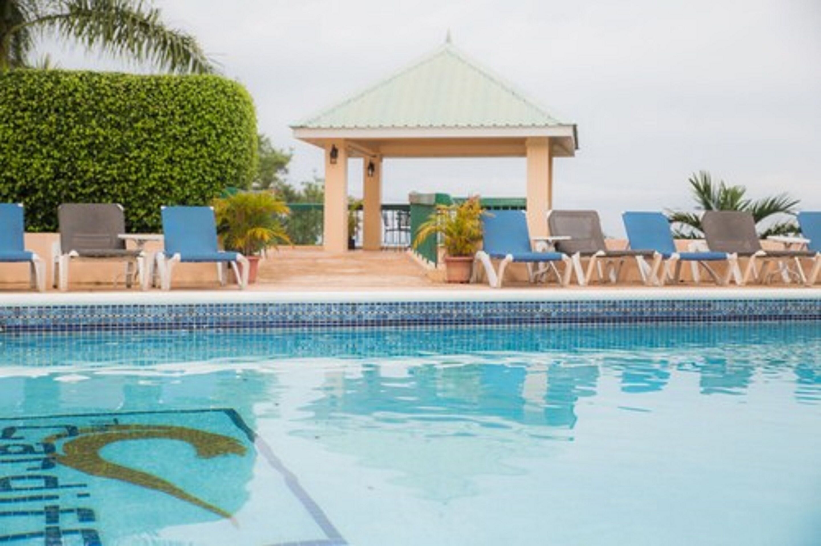 A swimming pool with lounge chairs and a gazebo.