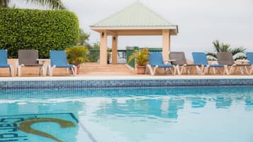A swimming pool with lounge chairs and a gazebo.