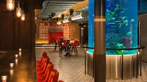 A bar area with red seating, a large aquarium, and exposed ductwork on the ceiling.