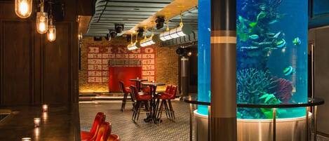 A bar area with red seating, a large aquarium, and exposed ductwork on the ceiling.