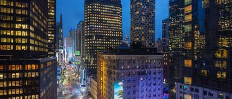 A cityscape at dusk with illuminated skyscrapers and a busy street.