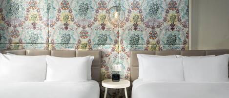 A hotel room with two beds, a small bedside table with a clock, and a decorative wall.