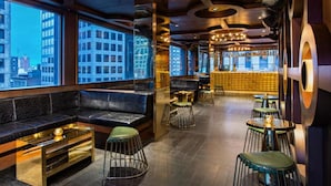 A modern lounge area with leather seating, metal stools, and a bar area with stools and a counter.