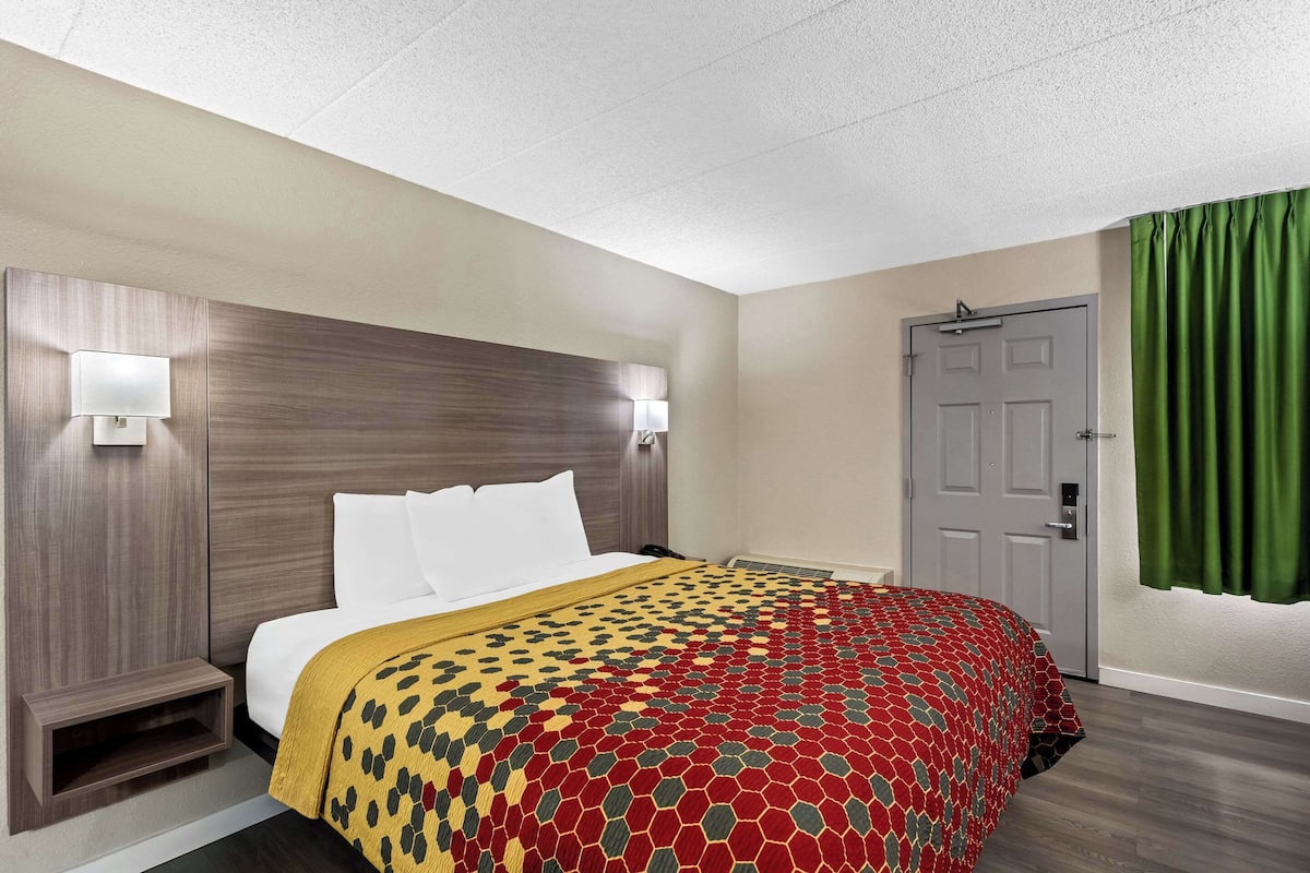 A hotel room with a bed, a headboard, a door, and a green curtain.