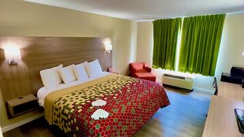Hotelkamer met een bed, nachtkastjes, een bureau, een stoel, een verwarming en een raam met gordijnen.