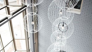 Een modern interieur met een groot raam, een blauw tapijt, een grijze bank en een opvallende bolvormige lamp.