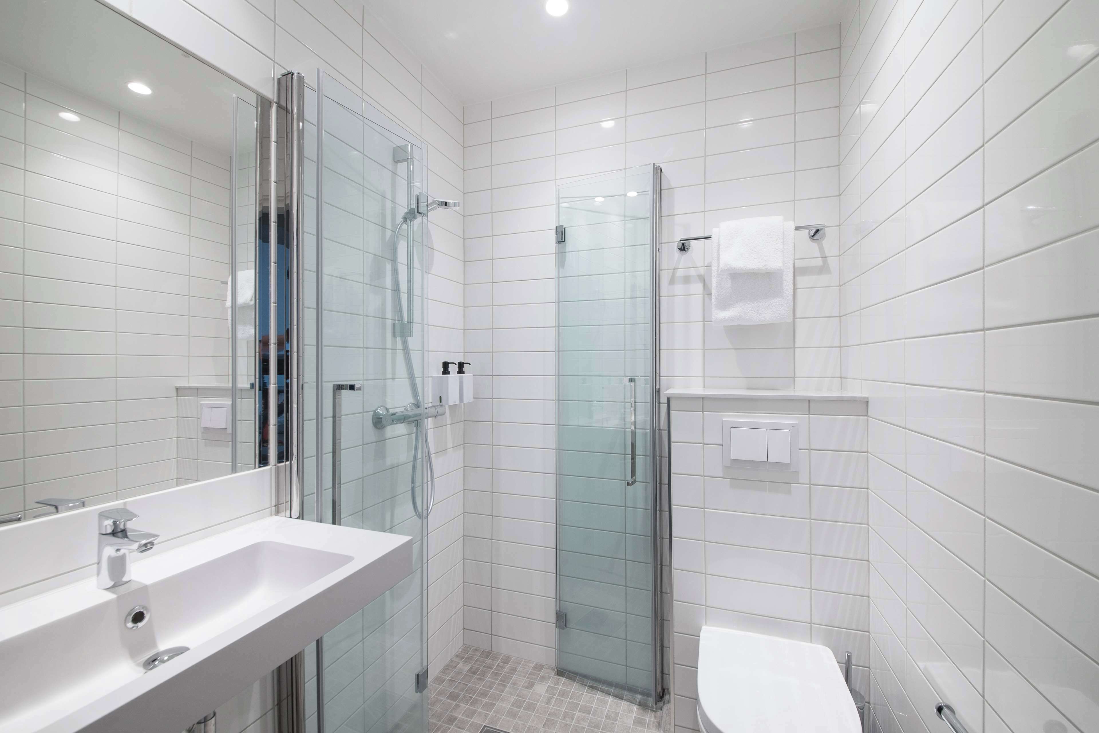 A modern bathroom with a glass shower enclosure, a white sink, and a toilet.