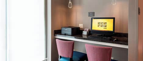 A modern workspace with a desk, two chairs, a computer, and a printer.