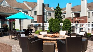 An outdoor patio area with wicker furniture, a fire pit, and a barbecue grill. - Residence Inn Syracuse Carrier Circle (East Syracuse)