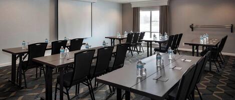 Un salón de conferencias con varias mesas y sillas, equipado con botellas de agua y tarjetas de identificación.