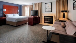 A hotel room with a bed, a TV, a sofa, a small table, and a fireplace. - Residence Inn Syracuse Carrier Circle (East Syracuse)
