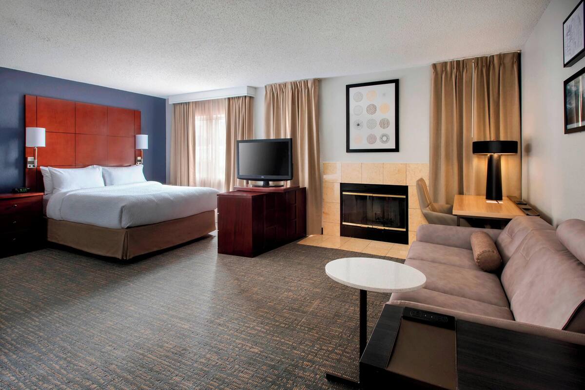 Une chambre d’hôtel équipée d’un lit, d’une télévision, d’un canapé, d’une petite table et d’une cheminée.