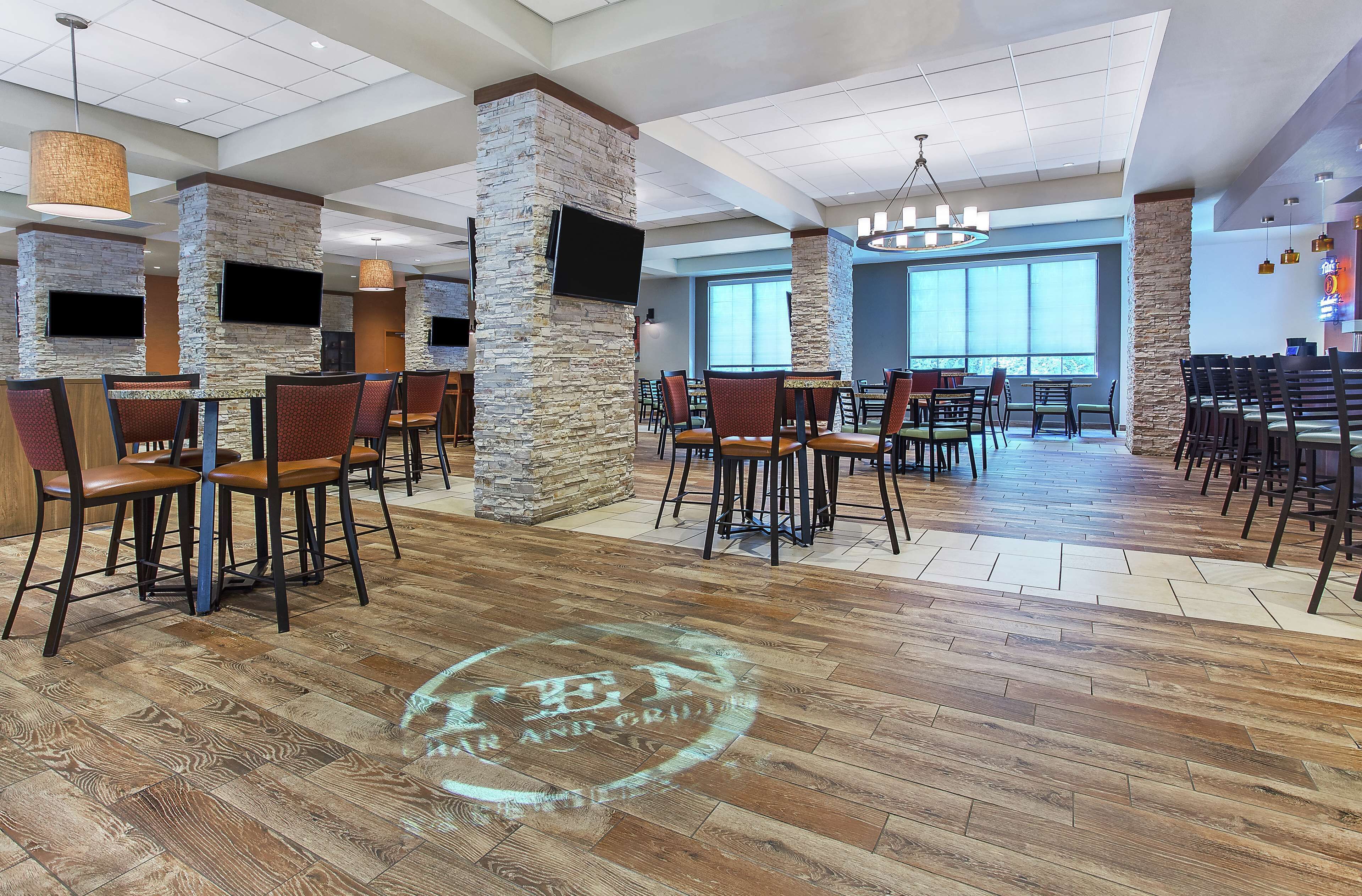 A spacious restaurant with high ceilings, stone pillars, and wooden flooring.