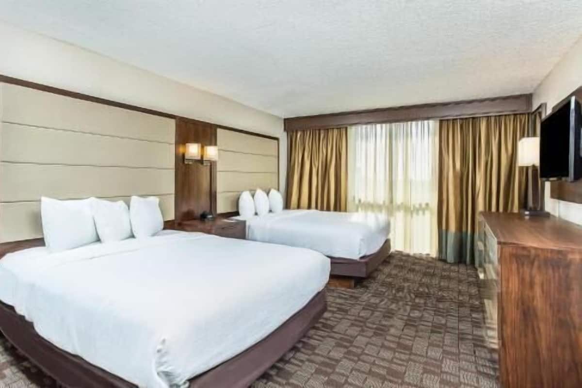 Ein Hotelzimmer mit zwei Betten, einem Fernseher und einem Schreibtisch.