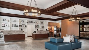 A hotel lobby with a reception desk, a blue sofa, and a wall decorated with framed photos.