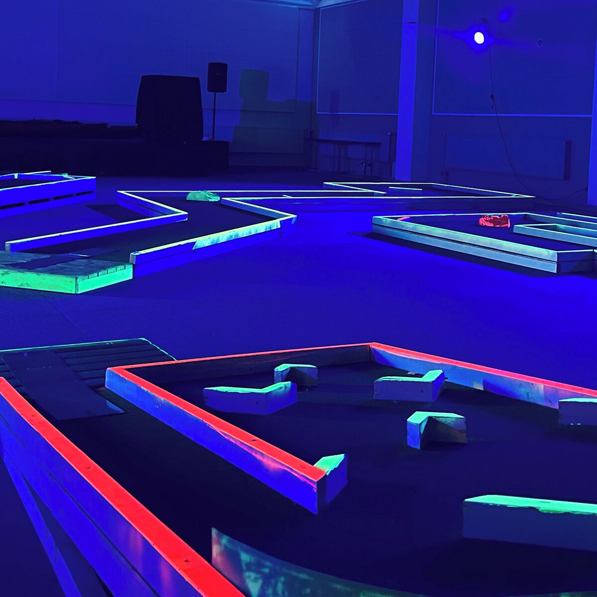 A room with a blue-lit floor, geometric shapes, and a projector screen.