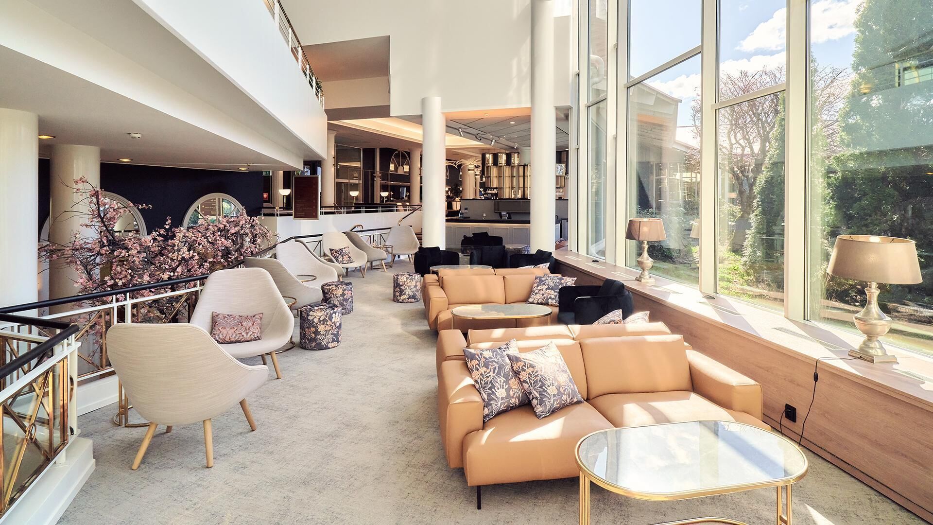 A spacious lounge area with seating, large windows, and a view of the outdoors.