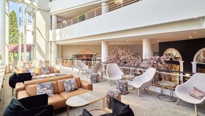 A spacious lobby with a high ceiling, multiple seating areas, and a central floral arrangement. - Naantali Spa Hotel (Naantali)