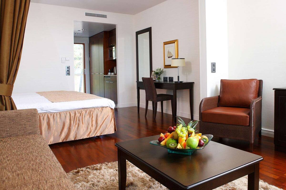 A hotel room with a bed, a desk, a chair, a television, and a fruit bowl on a table.