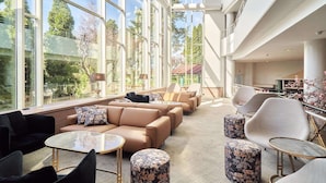 A spacious lounge area with large windows, comfortable seating, and a view of the outdoors. - Naantali Spa Hotel (Naantali)