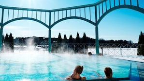 A pool area with a clear blue sky, a large arched structure, and people relaxing in the water. - Naantali Spa Hotel (Naantali)