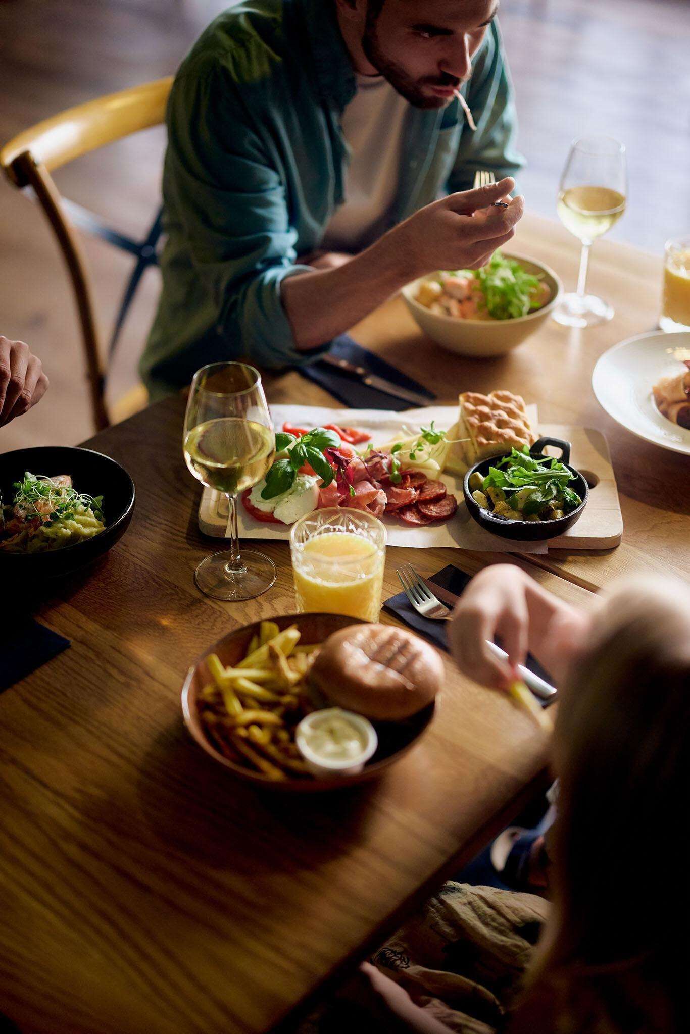 Une table à manger avec différents plats, notamment une salade, du pain et un bol de frites.