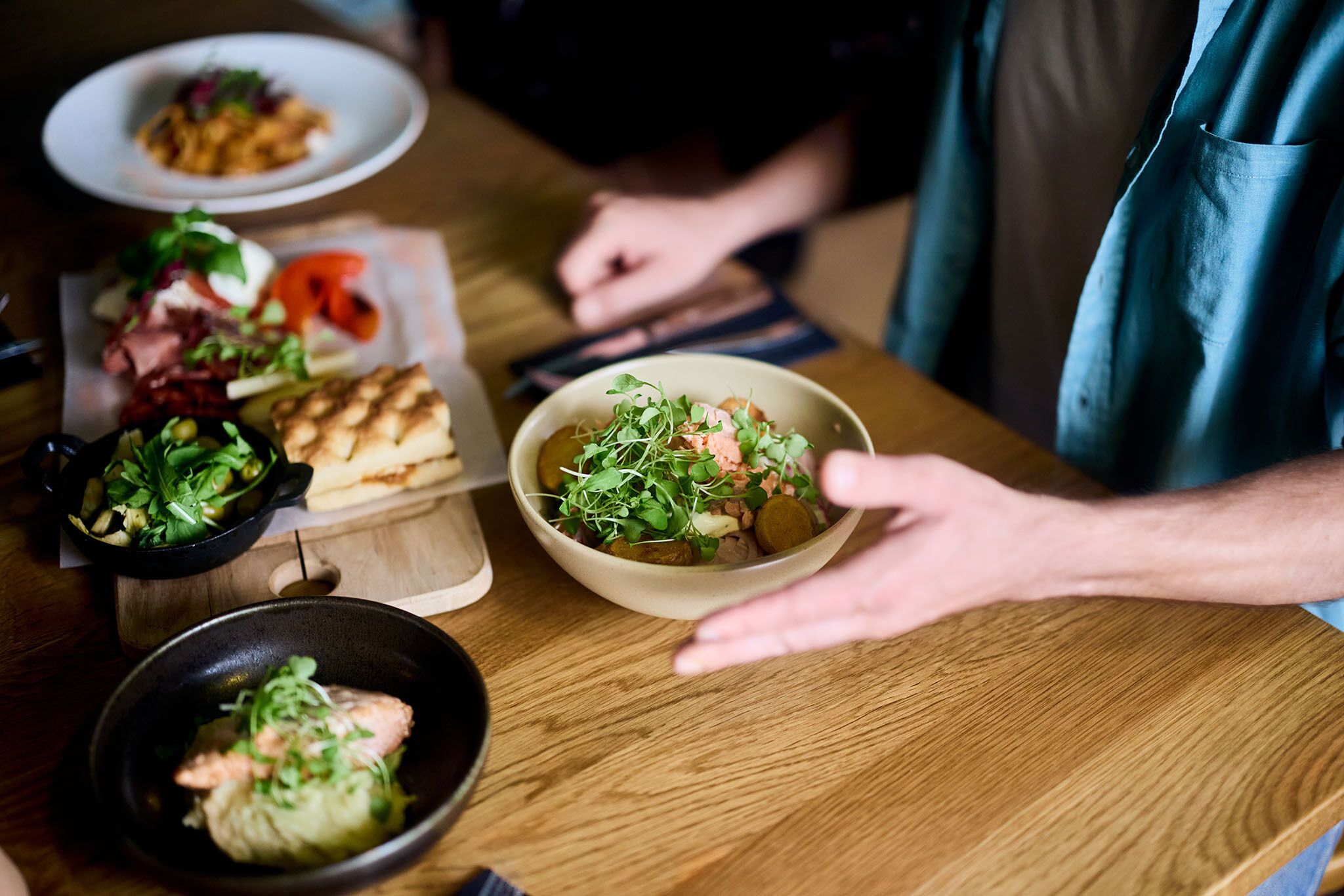 Een eettafel met verschillende gerechten, waaronder een saladeschaal, een soepkom en een bord eten.