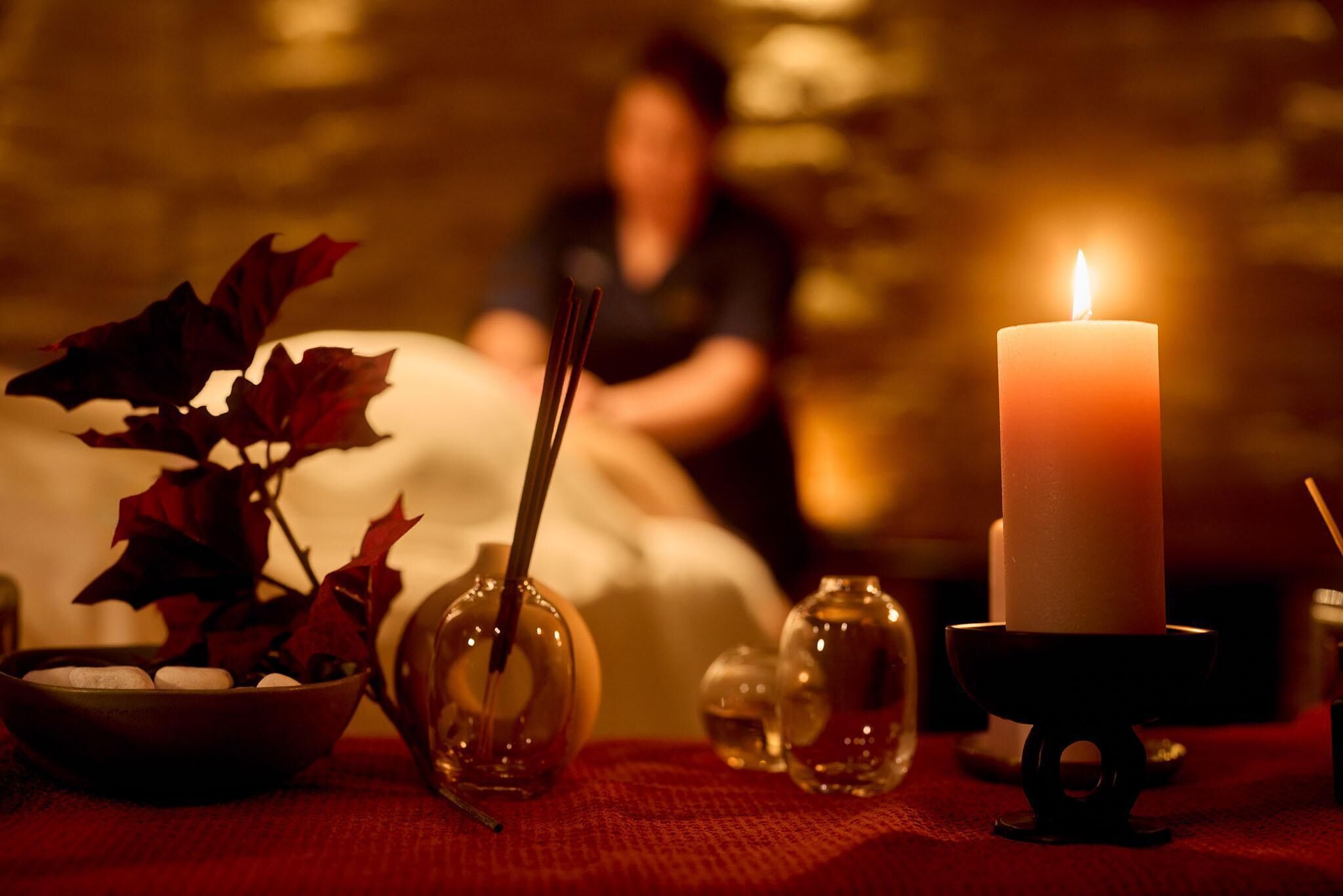 A candle, a bowl, and a vase on a table.
