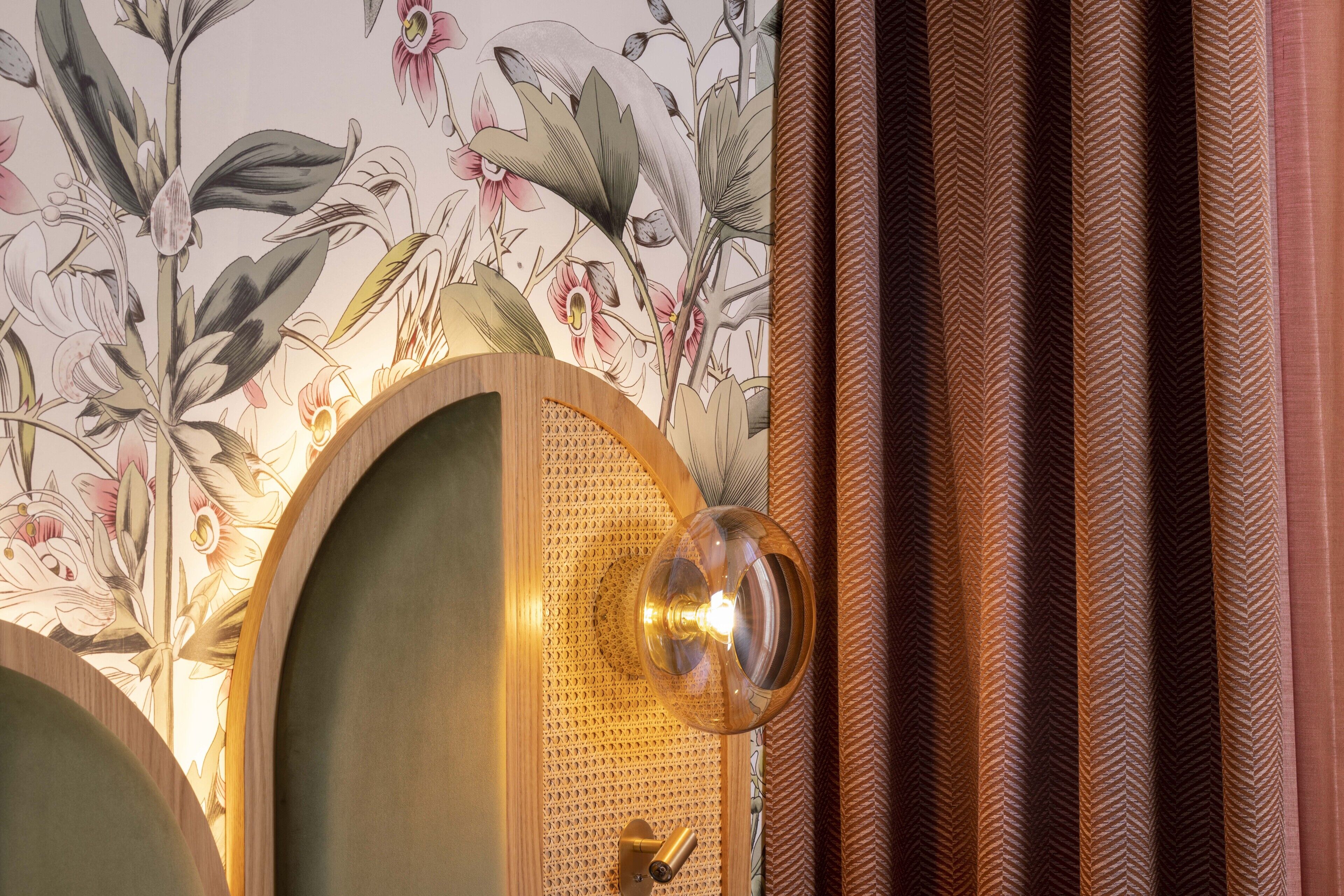 A room with a floral wallpaper, a wooden door, and a patterned curtain.