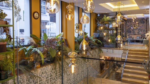 Un intérieur moderne avec un escalier, des rampes en verre et des luminaires suspendus.