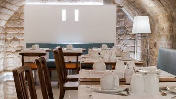 A restaurant with stone walls, wooden tables, and white table settings.